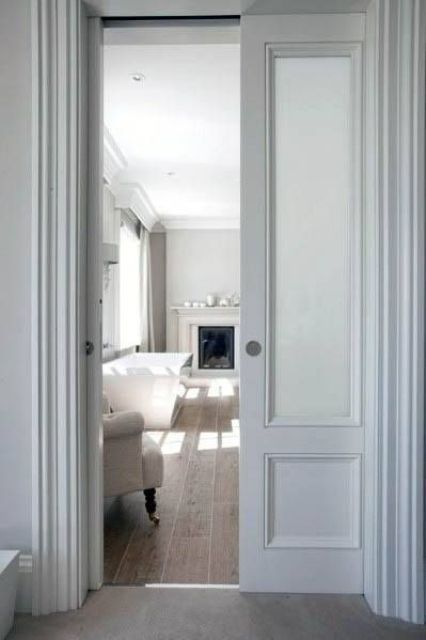 a white shabby chic space with matching pane pocket doors and elegant all-white furniture plus candles