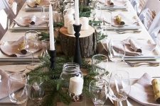 a woodland Thanksgiving tablescape with all neutral linens, evergreens, tree stumps with pillar candles, tall and thin candles