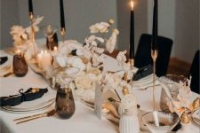 an elegant black and white Thanksgiving tablescape with black candles, lunaria and white vases, white porcelain and black napkins