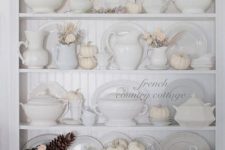 beautiful vintage white Thanksgiving decor with pumpkins, blooms and a pinecone plus neutral and white porcelain