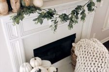 beautiful white Thanksgiving decor with wooden candleholders and lots of white pumpkins, a white chunky kniy blanket in a basket