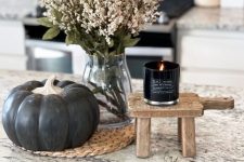 modern Thanksgiving or fall decor with a black pumpkins, a black candle and white blooms in a vase