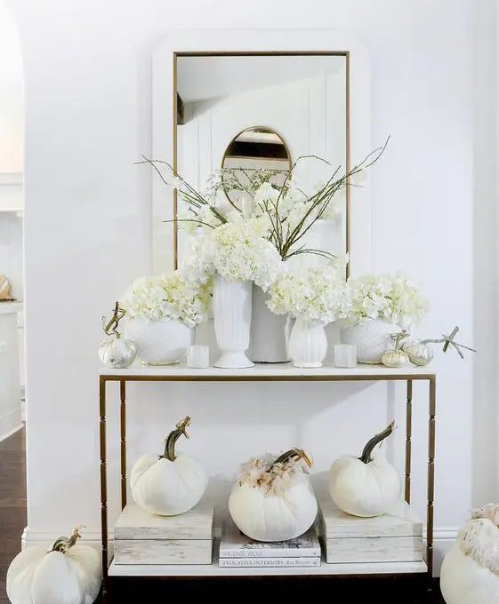 white Thanksgiving decor with fabric pumpkins and feathers, white vases and blooms is a beautiful idea for fall