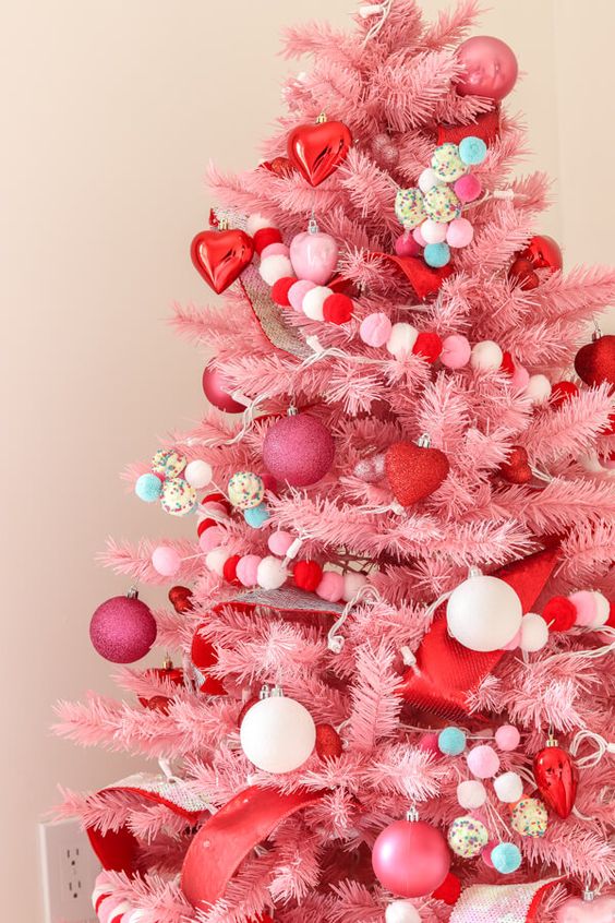 a pink Christmas tree decorated with pink and white ornaments, red hearts, pompoms is a very cool and out of the box idea to rock