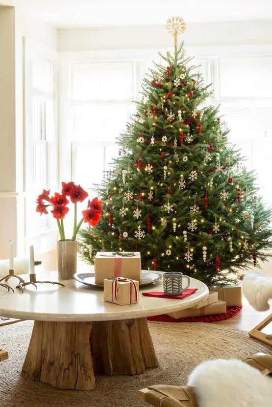 a traditional Scandi Christmas tree with gorgeous white snowflakes and red ornaments plus lights is a gorgeous holiday decoration and a bold statement in the space