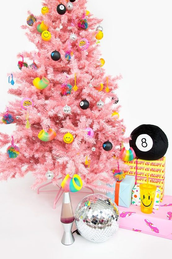 a bright pink Christmas tree with funny and colorful modern ornaments including emoji ones ooks fresh and very bold