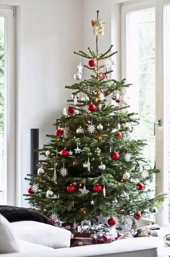 a traditional Christmas tree with white, red, metallic ornaments, balls, snowflakes and stars looks bold, catchy and screams holidays