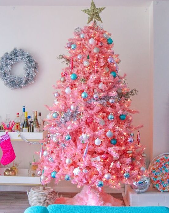 a candy pink Christmas tree with neutral, metallic and blue ornaments and lights looks very sweet and very cute