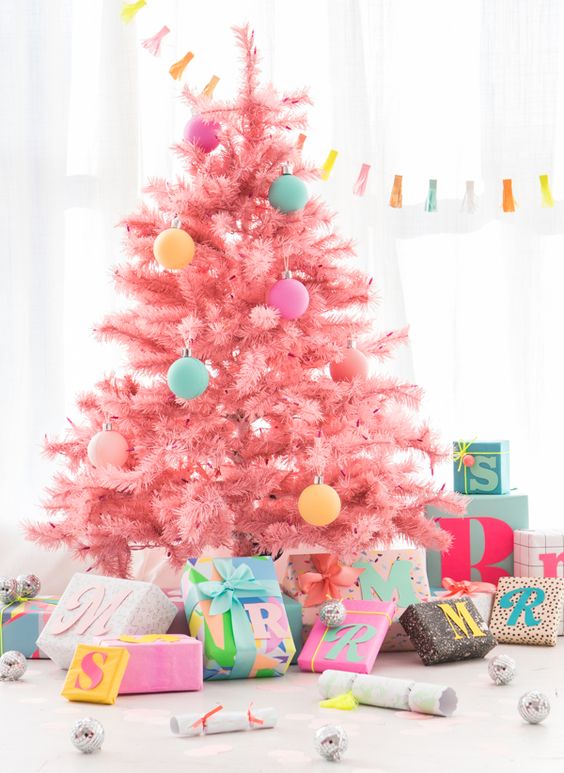 a cool candy pink Christmas tree decorated with a bit of pastelc-olored ornaments looks gorgeous, modern, fresh and very pretty