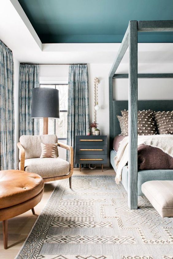 an oversized printed rug, heavy curtains and lovely layered bedding make this bedroom more welcoming