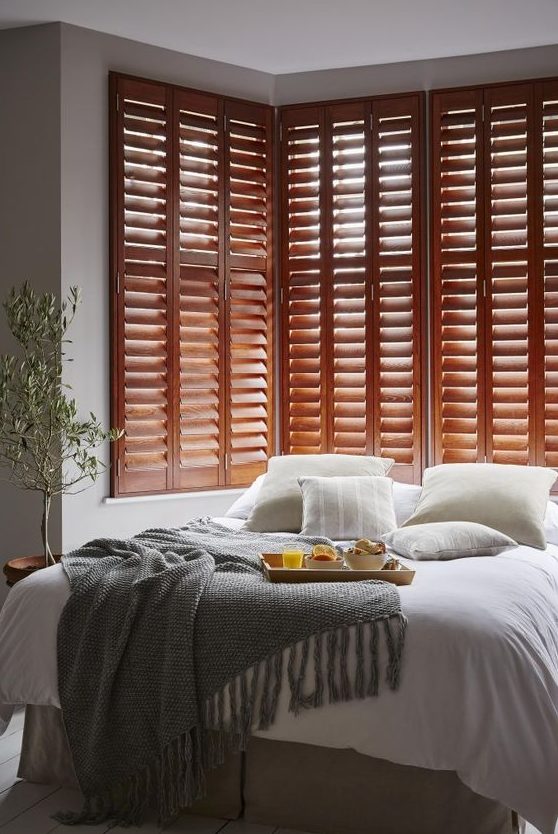 rich-stained shutters in the bedroom is a chic decor idea and a great alternative to a bed headboard