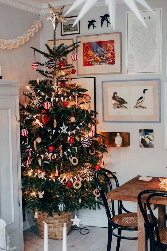 a classic Scandinavian Christmas tree with red and white ornaments, striped ones, buntings, lights and donut ornaments