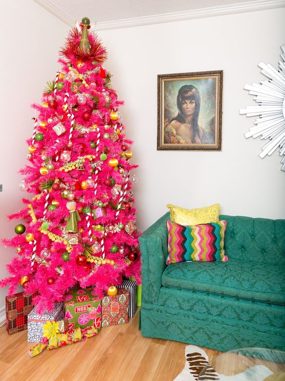 a hot pink Christmas tree with yellow and green ornaments, pompom garlands and fluffy banners is a very bold color statement that takes over the space
