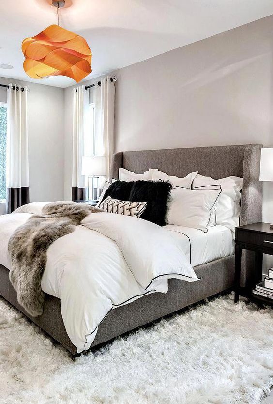 a faux fur oversized rug and layered bedding with a faux fur cover are amazing for a modern bedroom