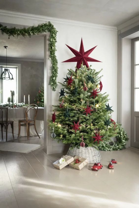 a fresh take on a classic Scandinavian Christmas tree with lights, oversized green and red stars and a red star topper