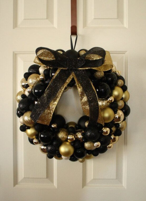 a beautiful black and gold Christmas wreath fully made of ornaments, with matching glitter bows is a gorgeous idea