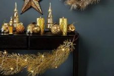 23 a black console table with oversized gold balls, gold patterned candles, a gold wreath and stars plus lights is amazing for the holidays