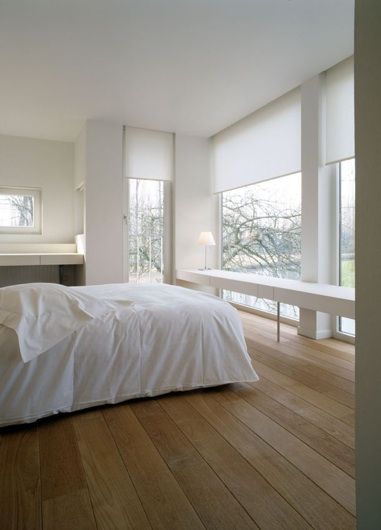 a minimalist neutral bedroom with large windows, sleek white blinds that echo with the furniture in the room