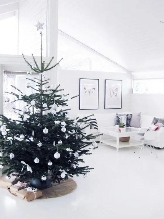 a modern Nordic Christmas tree with silver and white ornaments plus bows and a star on top is an airy and flowy decor idea for a modern Scandi space
