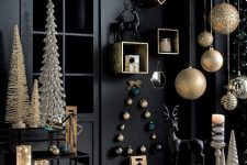 27 a refined Christmas space with black walls and furniture, oversized gold ornaments, deer, shiny Christmas trees and lights and candles