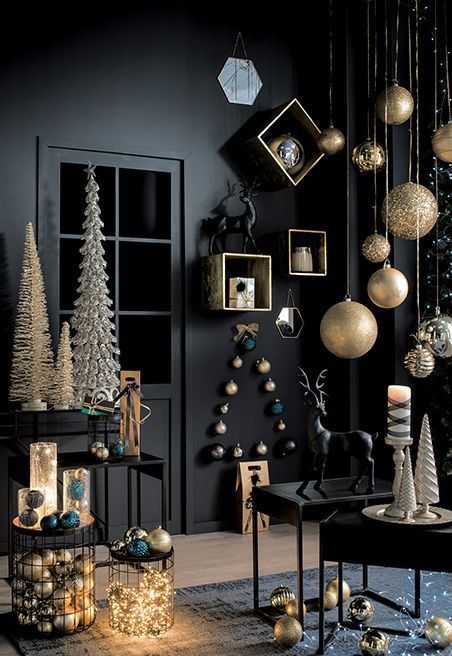 a refined Christmas space with black walls and furniture, oversized gold ornaments, deer, shiny Christmas trees and lights and candles