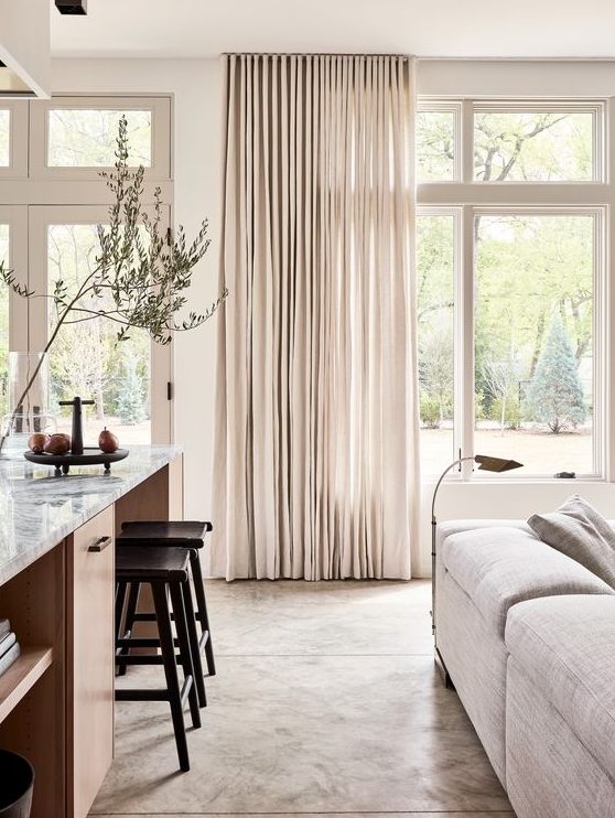 neutral drapes always add an airy feel to the room making it more welcoming and visually taller if you attach them to the ceiling