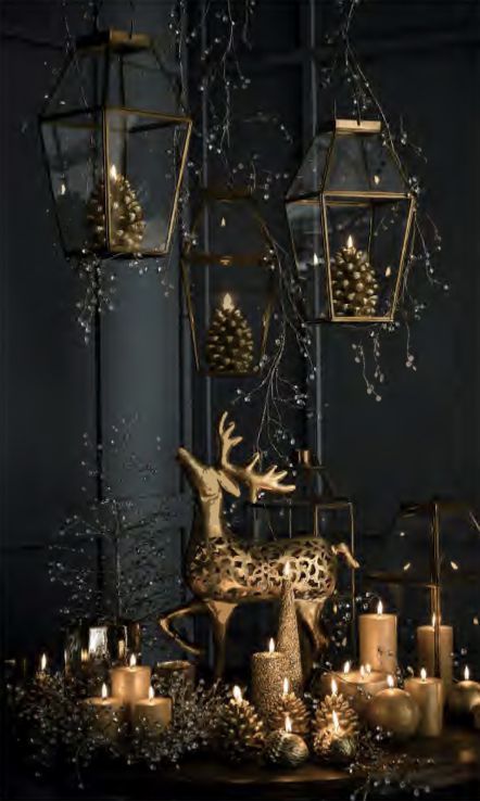 beautiful Christmas decor with pendant gold lanterns with pinecone candles, gold candles, a gold deer and everything black around