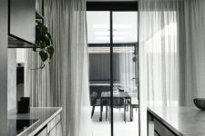 29 a dramatic black and grey minimalist home with matching light sheer grey curtains that fit the color scheme and add an airy feel to it