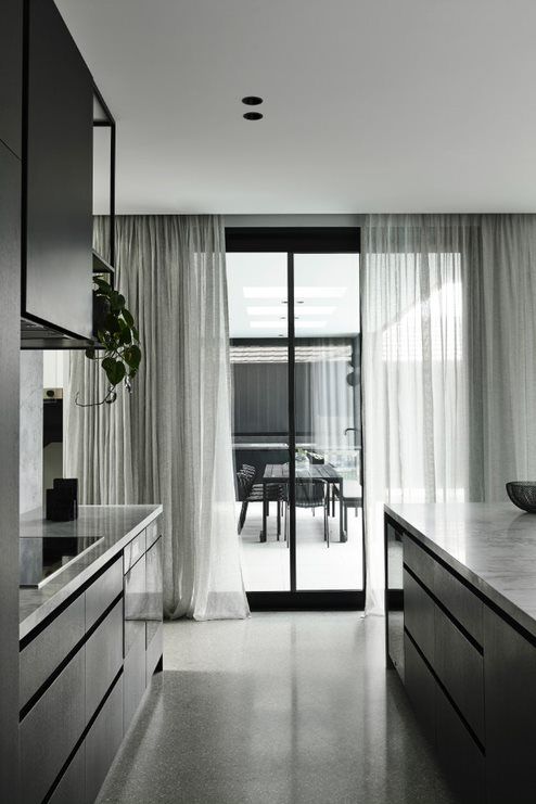 a dramatic black and grey minimalist home with matching light sheer grey curtains that fit the color scheme and add an airy feel to it