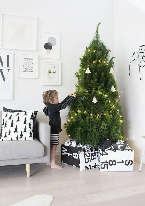 a modern Nordic tree with lights and white tree-shaped ornaments plus himmeli ones and black and white printed wrapped gifts is a lovely idea for a modern space