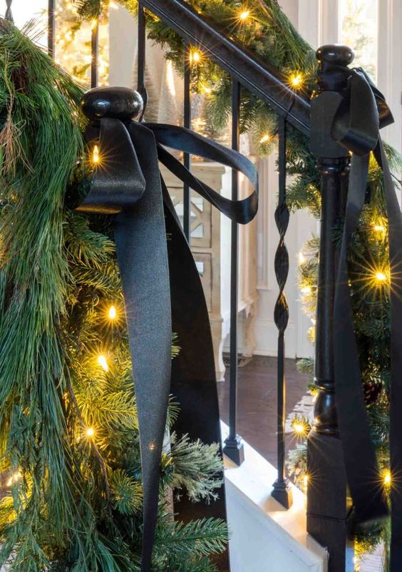 elegant Christmas decor with black ribbon bows, evergreens and lights is chic and simple and will bring elegance to your space