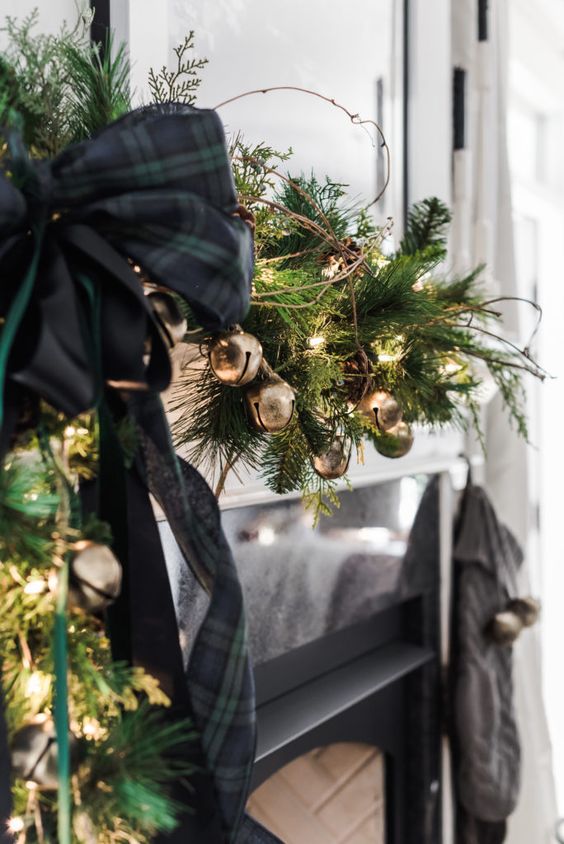 lovely festive decor with an evergreen and gold bell garland, black plaid ribbon bows, twigs and lights is great for Christmas
