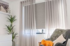 33 a kid’s space with a window treated with grey blinds and semi sheer light grey curtains that are mainly for decor