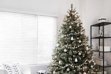 33 a modern Scandinavian tree with pompom ball garlands, metallic ornaments and tree-shaped ornaments plus lights