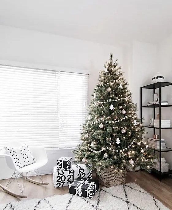 a modern Scandinavian tree with pompom ball garlands, metallic ornaments and tree shaped ornaments plus lights