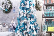 35 a bold turquoise Christmas tree decorated with white and silver ornaments, ribbons, snowflakes feels and looks very frosty