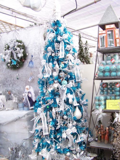 a bold turquoise Christmas tree decorated with white and silver ornaments, ribbons, snowflakes feels and looks very frosty