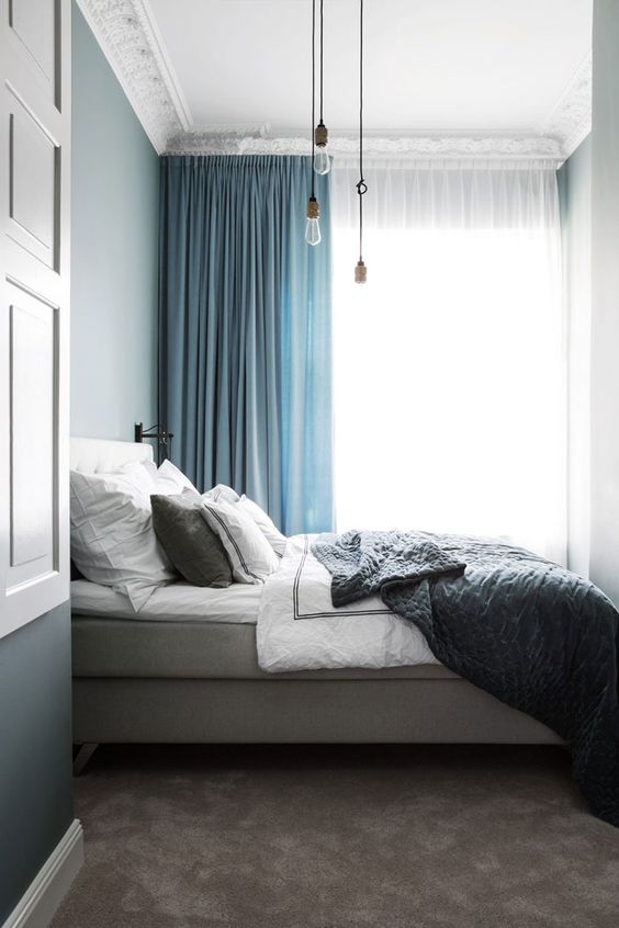 semi sheer white and thick blue curtains attached to the ceiling make this small bedroom look higher