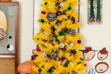 40 a small yellow Christmas tree with green and purple ornaments is a fresh and crazy color combo that you may rock to stand out