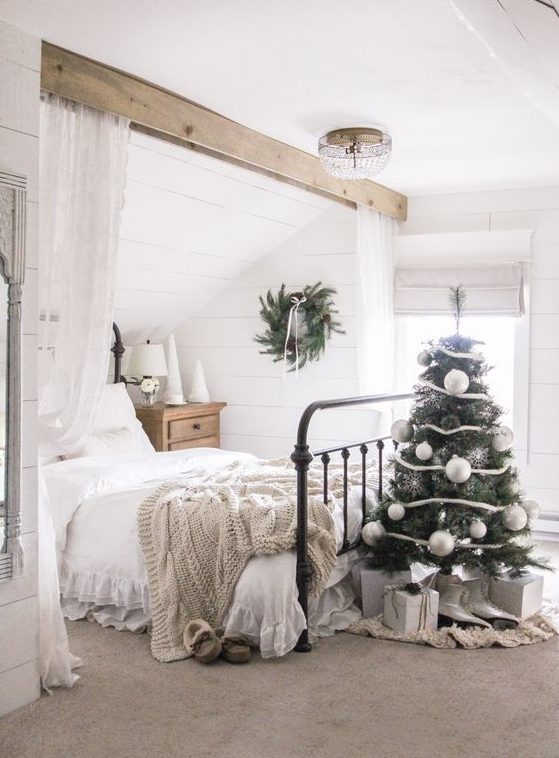 a Christmas tree decorated with white ribbons, silver snowflakes and oversized white ornaments for a farmhouse space