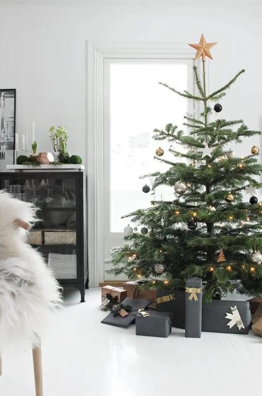 a Christmas tree with black, silver and gold ornaments and gold star topper and lights is modern and chic elegance