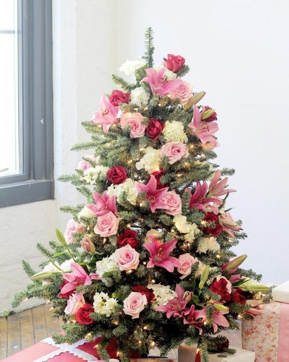 a Christmas tree with light pink, bold pink and neutral blooms covering the tree and lights for a more festive look