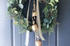 a beautiful Christmas wreath of evergreens and greenery, oversized bells and a striped bow is a very chic and non-typical solution