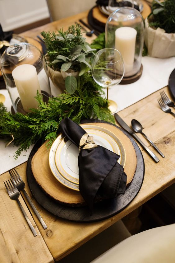 a beautiful black and gold Christmas tablescape accented with potted greenery and pillar candles is wow