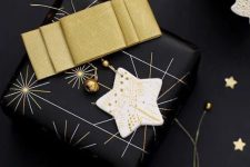 a black Christmas gift wrapped with a gold bow, a clay star ornament and smaller gold ones is lovely and very chic