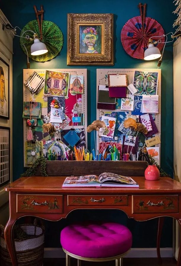 a boho maximalist home office with a navy accent wall, a vintage desk, a hot pink stool, a gallery wall and memo boards plus lights