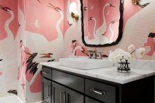 a bold bathroom with geometric tiles on the floor, pink bird print wallpaper, a black vanity, a white countertop and a sink and a catchy mirror