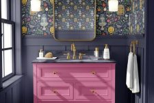a bold maximalist bathroom with graphite grey paneling, dark floral wallpaper, a hot pink vanity and gold touches