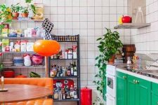 a bold maximalist kitchen with emerald cabinets, white tile walls, orange upholstered benches and lamps