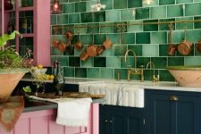 a bold maximalist kitchen with teal and pink cabinets, a green tile wall, a pink kitchen island and a wooden stool plus brass cookware